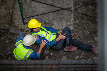 A young Asian builder falls from a scaffold at a construction site. An engineer supervising the...