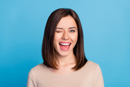 Portrait of overjoyed satisfied lady eye wink beaming smile isolated on blue color background