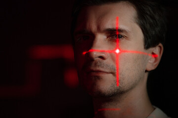 Purpose, technology and human, concept. A young man with projections of red patterns on his face, scanning, verification or interaction with augmented reality.