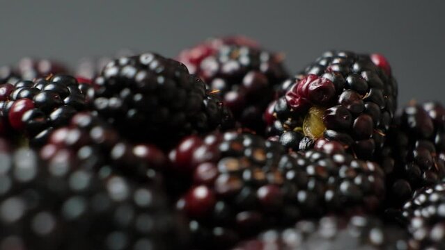 Ripe juicy blackberries swirling on a black background, slow motion.
