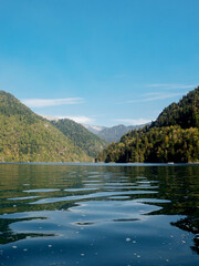 A beautiful lake in the mountains, the water surface reflects the mountains and the forest.