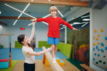Kids doing balance beam gymnastics exercises in gym at kindergarten or elementary school. Children...