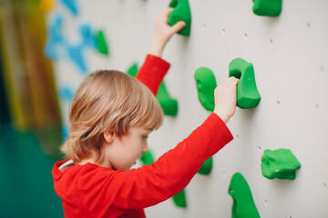 Kid child boy at climbing wall. Children sport, healthy lifestyle in kindergarten or sport center in school.