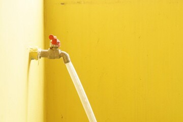 Faucet with hose on yellow wall