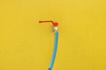 Faucet with hose on yellow wall