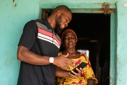 african man explaining to an elderly african woman with phone
