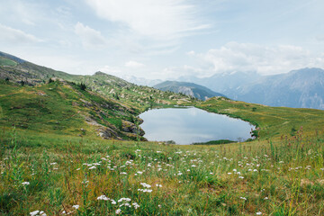 Fototapeta na wymiar Un lac de montagne. Un petit lac dans les Alpes. Une petite réserve d'eau dans les Alpes. Un petit lac à Vaujany. Une prairie de montagne avec un lac.