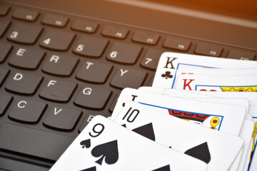 Paper cards on blank laptop keyboard, soft and selective focus, concept for playing  cards online with other people at home and recreational activity.
