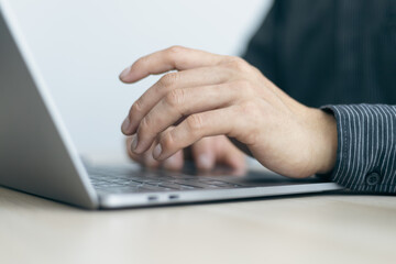 Close-up of man hands working on laptop keyboard.
