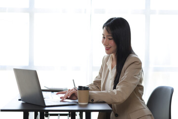 Attractive beautiful Asian business woman working on laptop on desk in office.