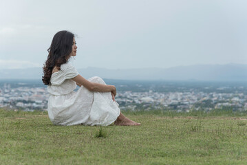 woman sit facing side on grass at top mountian look at sky  nature view.