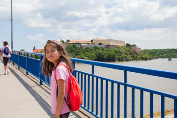 Fototapeta na wymiar Portrait of smiling child which crosses the bridge over the river Danube at Petrovaradin, Novi Sad, Serbia.