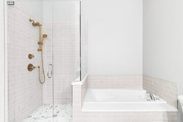 A bathroom with a renovated shower and bathtub. The shower features a gold faucet, subway tile...