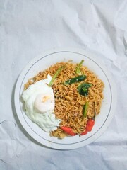 Tasty mie instant or instat noodle (Indomie Goreng) with egg and chili. Served on white plate. Isolated on white paper background,selective blurred focus