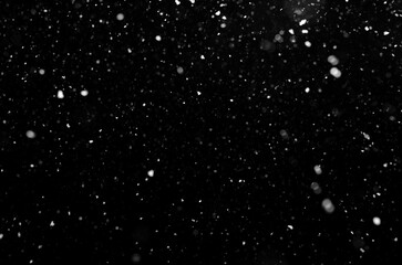 Fototapeta na wymiar falling snow out of focus, isolated on a black background