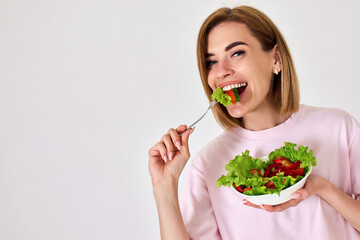 beautiful woman eating fresh vegetable salad on white background