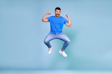 Fototapeta na wymiar Full length body size view of nice cheerful guy jumping rejoicing having fun great news isolated on bright blue color background