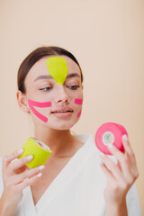 Beautiful woman applying tape lifting treatment procedure on face