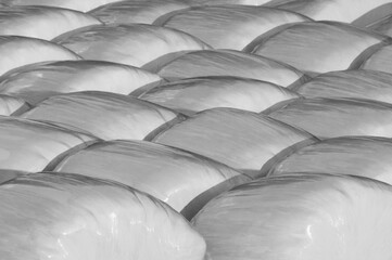 Faded black and white background of plastic wrapped hay bales 