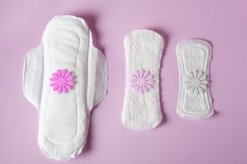 Three types of women's sanitary napkins for different intensity of menstruation on a pink background