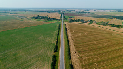 Aerial view of straight road with car between agricultural fields. View from drone.