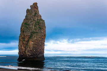 seascape of Kunashir, ocean shore with a huge vertical rock in the water and a wild beach with...