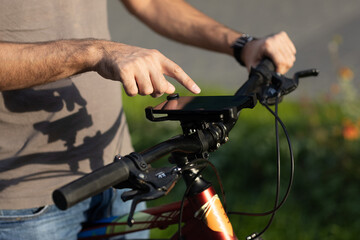 Man planning route pointing finger touch screen GPS navigation application in mobile phone on his bicycle bike
