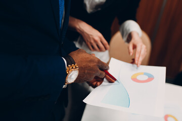 Businessman and businesswoman accountant team showing graph chart at office meeting. Business people group conference discussion sit at table with boss man and woman close up hands