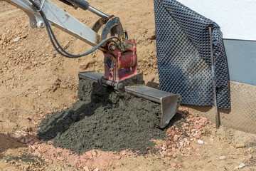 wet concrete placed with a digger scoop at the clay ground