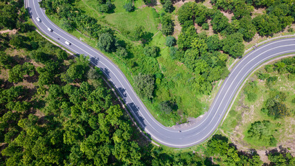 Aerial view of road going through greenery, Roads through the green forest, drone landscape - obrazy, fototapety, plakaty