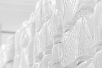 Obraz premium Many new rolls of toilet paper and paper towels sealed in stock. Light industry. Production of essential goods. Light background.