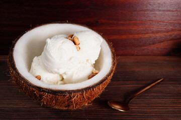 Coconut ice cream and halved coconut on wooden table (spot focus)
