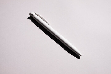 a white pen lies in the center on a gray background