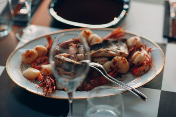 grilled seafood and fish lie on an oval platter on the table.