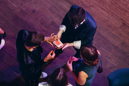 magician shows guests card tricks at the party top view.