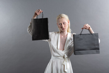 White caucasian albino blond woman holds shopping bag. Sale and discounts on market and Black...