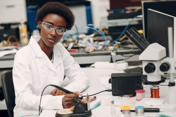 Scientist african american woman working in laboratory with soldering iron. Research and development of electronic devices by color black woman.