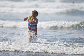 A young girl wearing a tie-dye shirt playing in the water near shore at Westport, Washington.