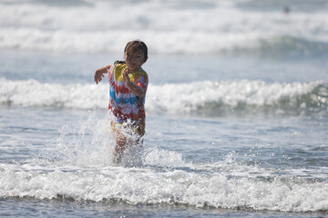 Fototapeta premium A young girl wearing a tie-dye shirt playing in the water near shore at Westport, Washington.
