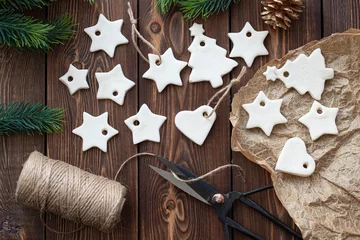 Weihnachtsdekoration aus gesalzenem Teig in Form von Sternen und Herzen liegen auf einem Holztisch. © Елена Швецова