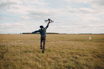 Man pilot holding quadcopter drone in hands at outside field