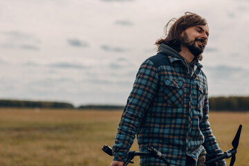 Man pilot holding quadcopter drone in hands at outside field