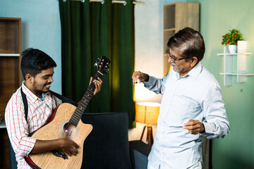 focus on old man, Happy father with son dancing by playing guitar at home - concept of leisure...