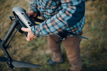 Man pilot checking quadcopter drone battery replacement and charging before aerial flight and filming