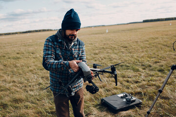 Man pilot checking quadcopter drone before aerial flight and filming