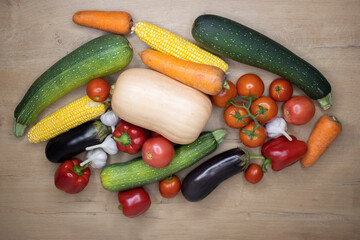 Top view autumn harvest vegetables on a wooden table. Ingredients for cooking: pumpkin, tomatoes, corn, carrots, zucchini, eggplant, garlic, pepper. Happy Thanksgiving. harvest