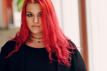 European plus size woman portrait outdoor street city. Young red pink haired body positive girl.