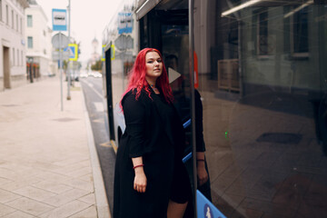 European plus size woman gets on the bus. Young red pink haired body positive girl.