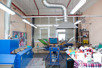 Serigraphy silk screen print process at clothes factory. Frame, squeegee and plastisol color paints.