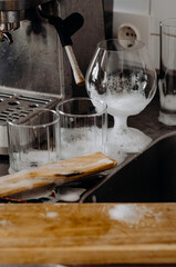 washing dishes:  glasses and temware, a wooden board and a spatula in foam near the sink. home life and housekeeping. cleaning in a dirty kitchen